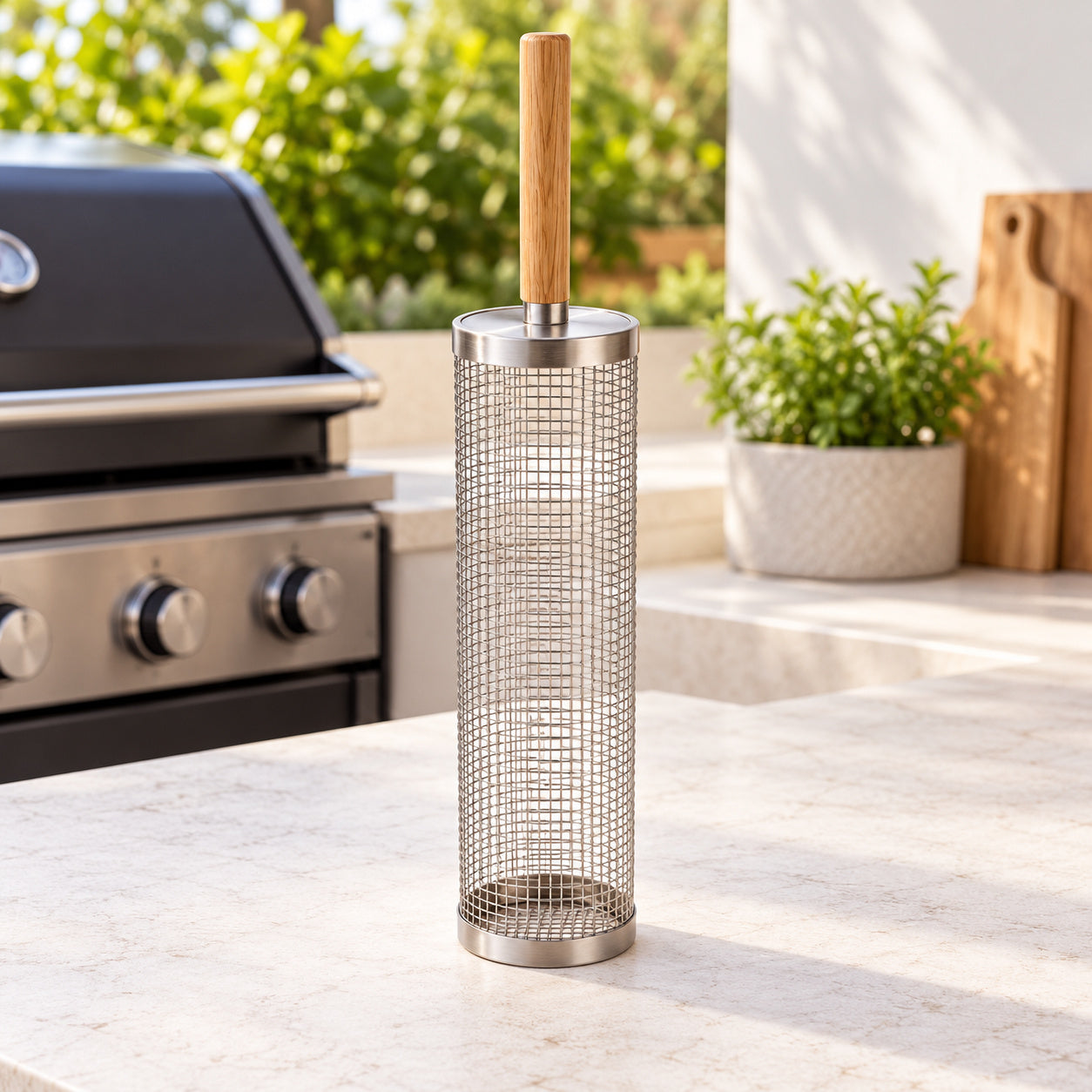 Stainless steel rolling grill basket with wooden handle beside a grill